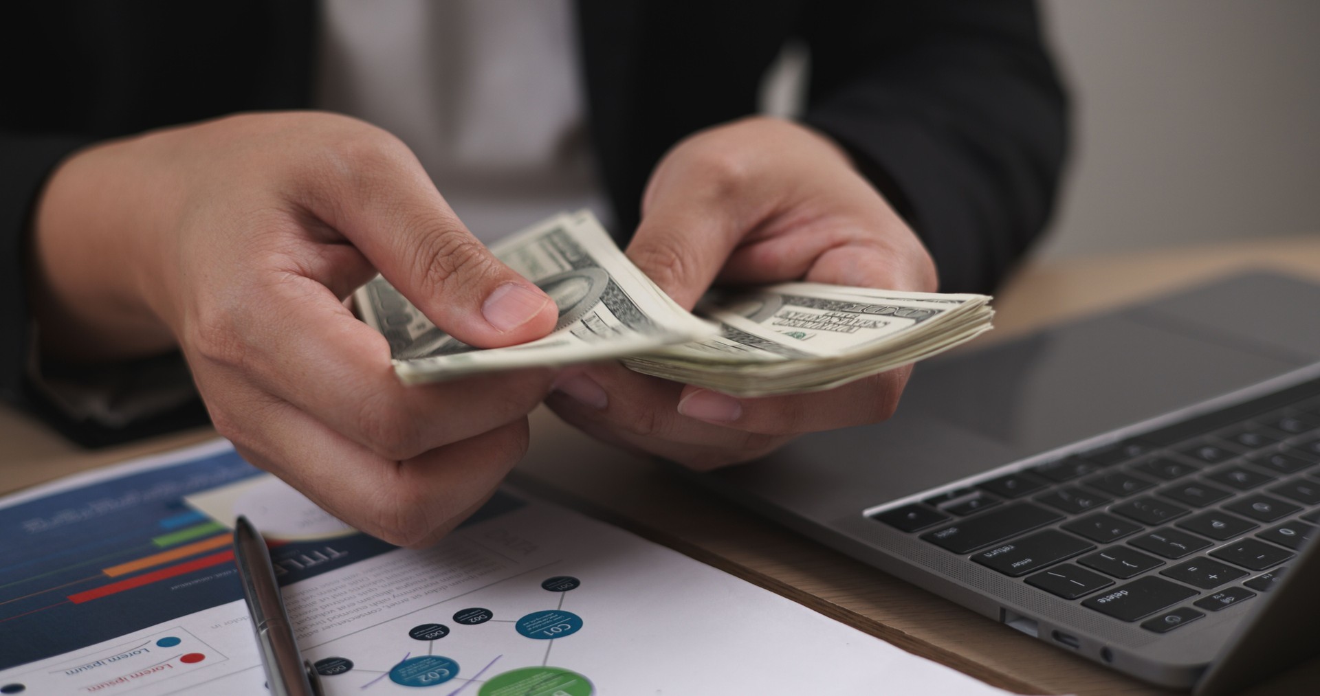 Portrait of Businessman holding banknotes and cash using a laptop